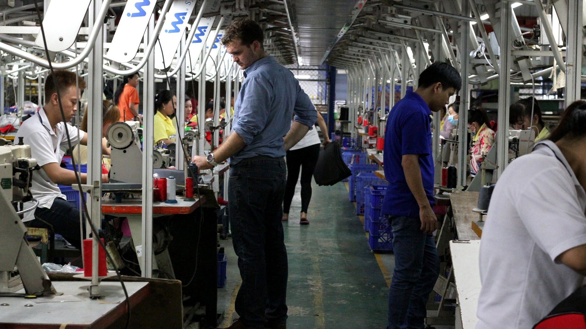 Factory workers operating sewing machines in a garment production line, illustrating ethical working conditions.