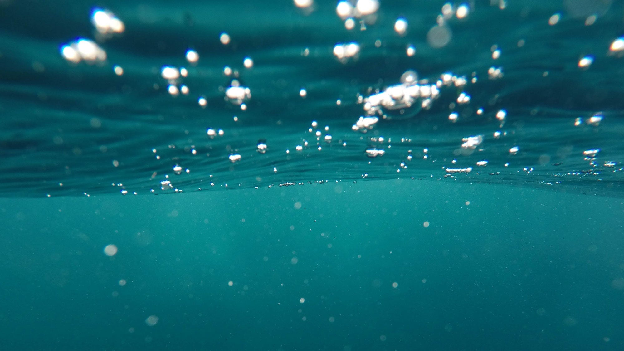 Underwater view with rising air bubbles in blue water, illustrating ocean pollution context.