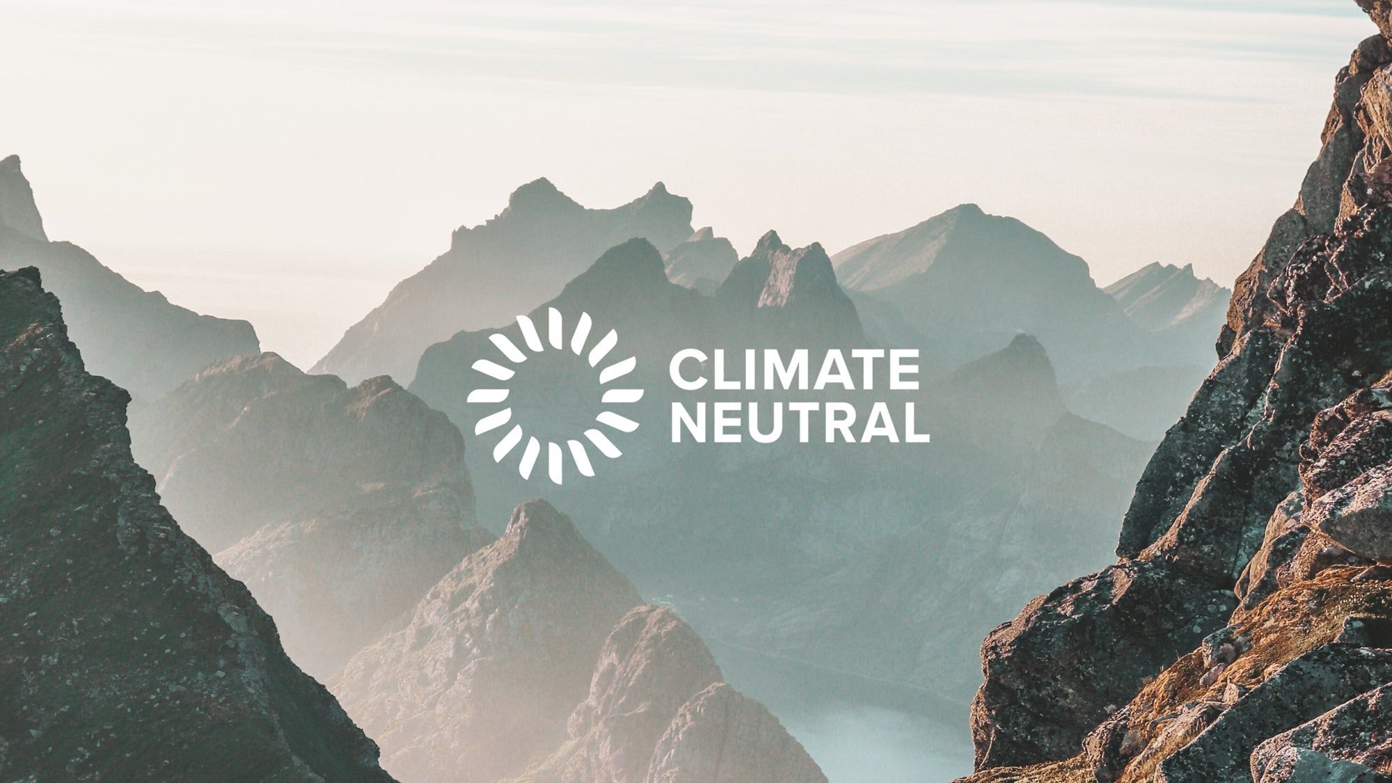 Mountain landscape with a circular emblem and the words 'CLIMATE NEUTRAL' in white text
