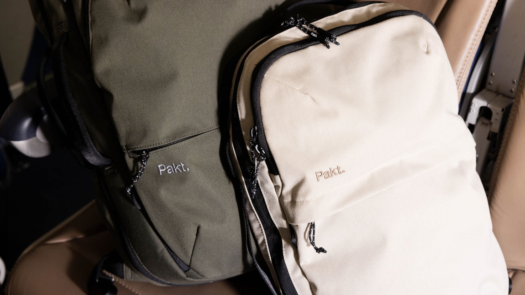 One Sand Everyday 15L Bag laying up against the Forest Travel Backpack. Both with the brand name 'Pakt' embroidered on the front pocket.