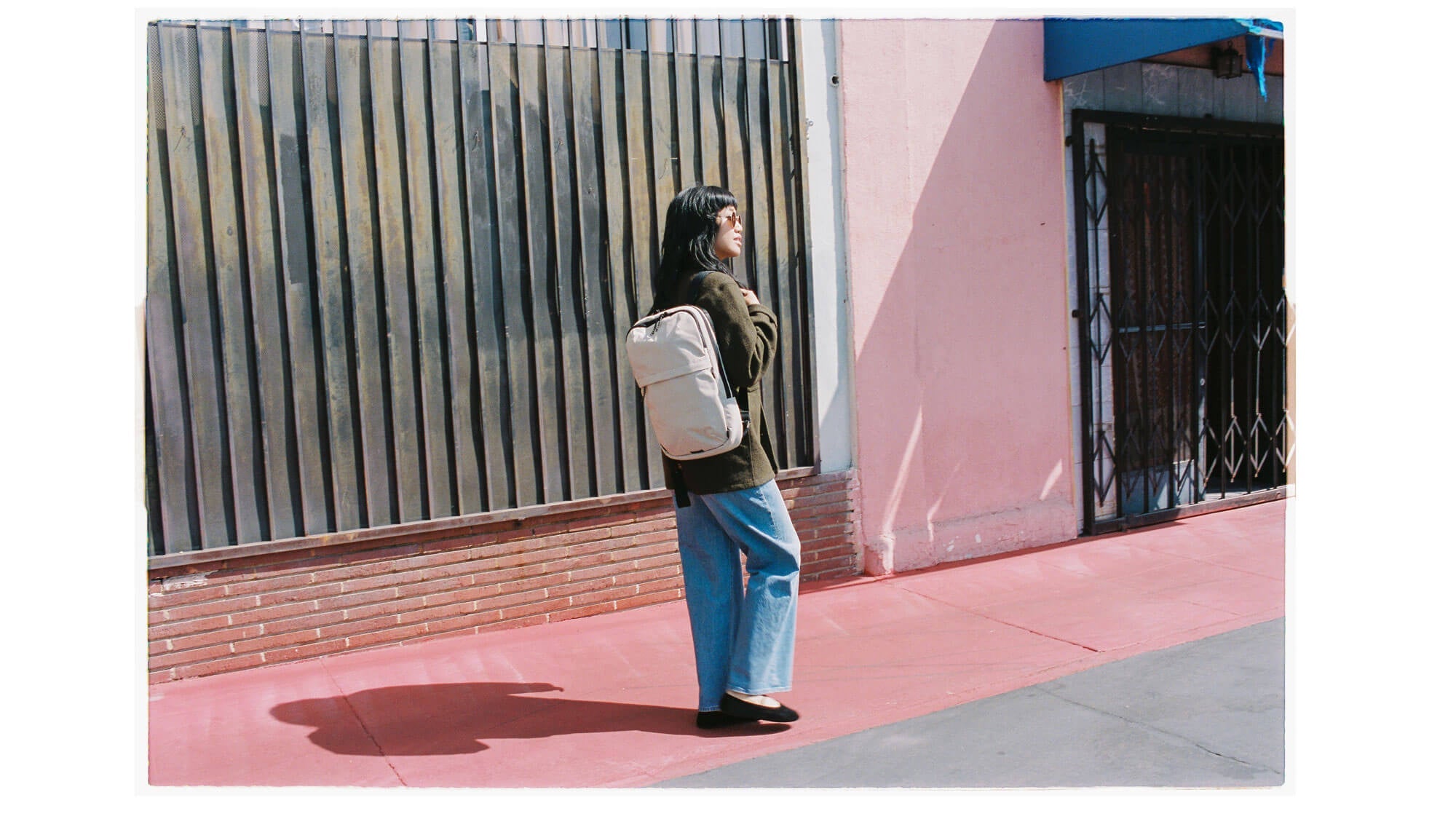 Woman walking in front of a pink wall with the Grandcart 15L Bag