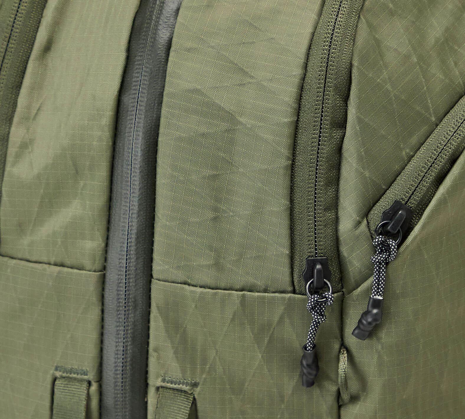 Close-up of the Cypress Aero Travel Backpack showing the fabric with two black zipper pulls on a travel bag or backpack.