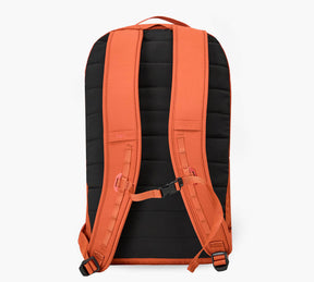 Back view of an orange Stash packable backpack showing padded shoulder straps, sternum strap, and quilted back panel.