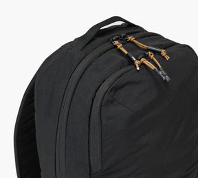 Close-up of black backpack top showing two zip compartments and tan paracord zipper pulls