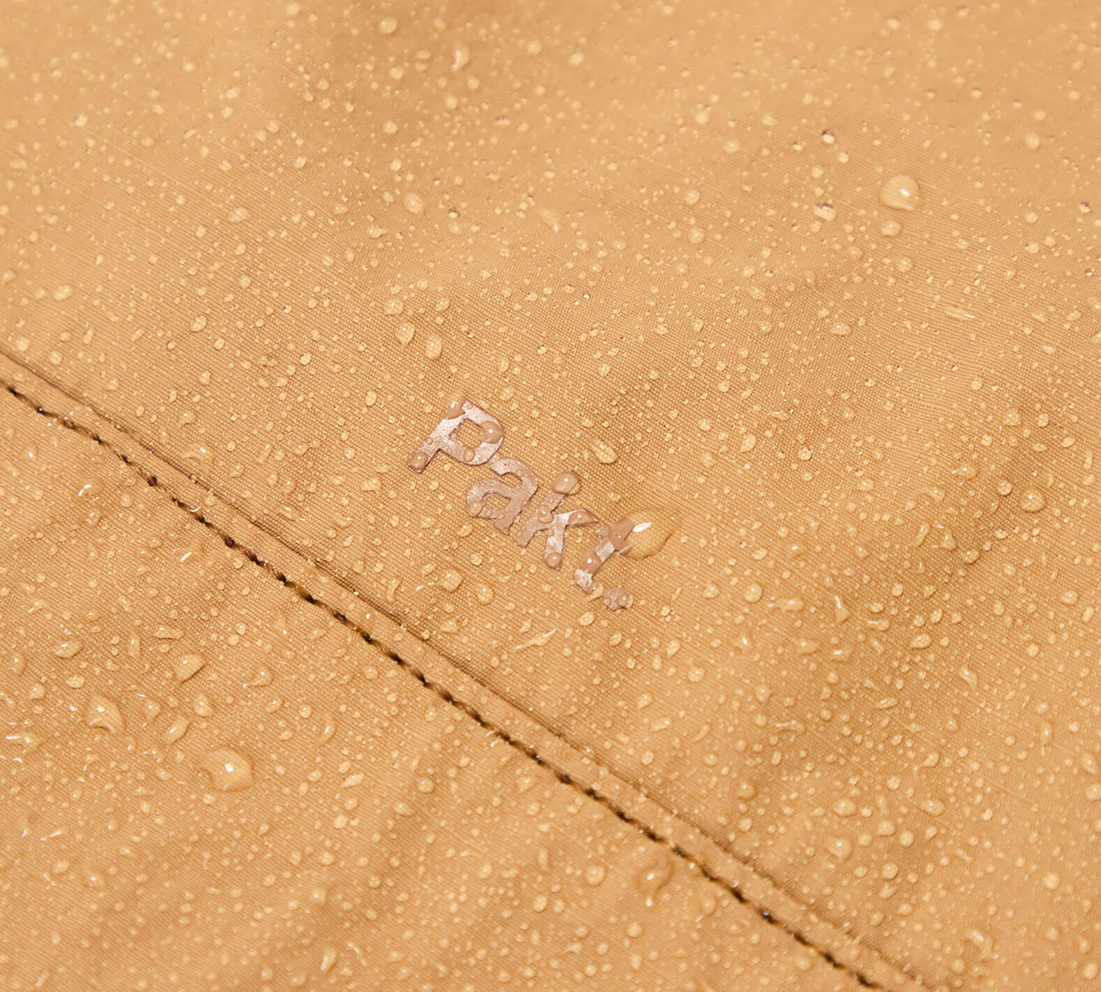 Close-up of the Mojave aeroweave fabric with water droplets and the word 'Pakt' embroidered.