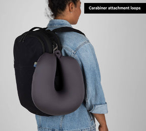 Backpack with travel neck pillow clipped to shoulder strap; label reads 'Carabiner attachment loops'