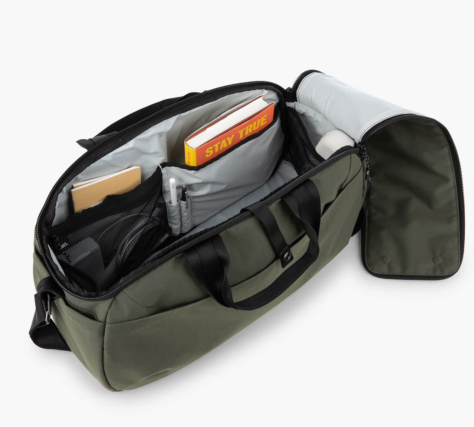 25L travel duffel, open to show interior pockets and a book titled 'STAY TRUE'.