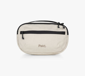 Beige canvas sling bag with black zipper, front pocket and "Pakt." embroidered logo