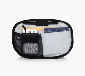 The Everyday 3L SLing with multiple compartments, including a mesh pocket and a larger fabric pocket, containing various small items, on a white background.