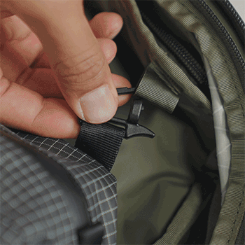 Hand attaching a Clip-In Pouch inside of the Aero Travel Backpack.