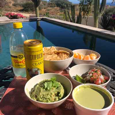 Poolside snack: guacamole, chips, pico de gallo, green salsa, orange segments, Topo Chico, PACIFICO CLARA.