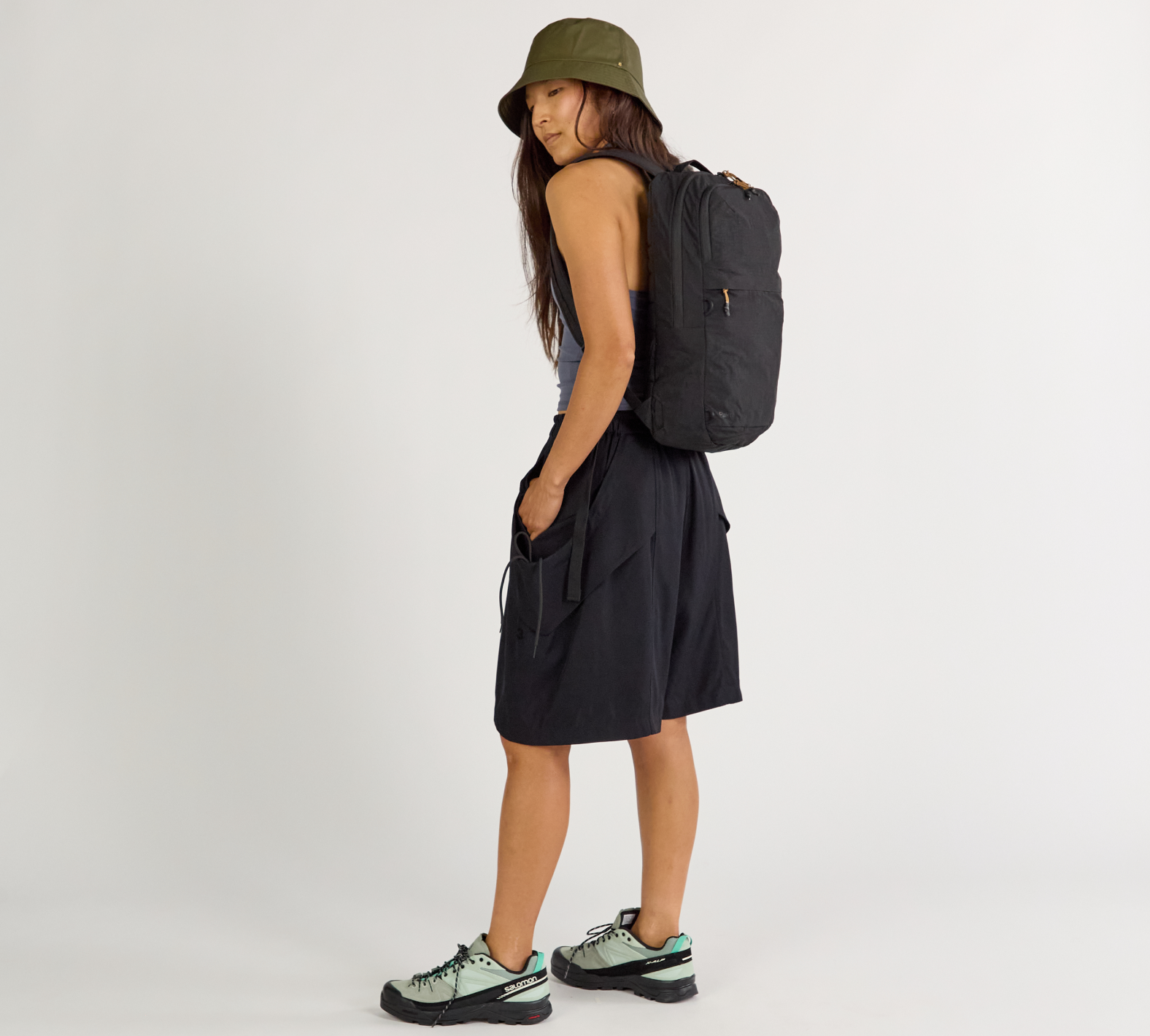Person wearing a black backpack and black outfit on a white background