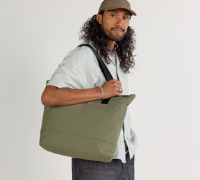 A model wearing the Stash tote in cypress against a plain background.