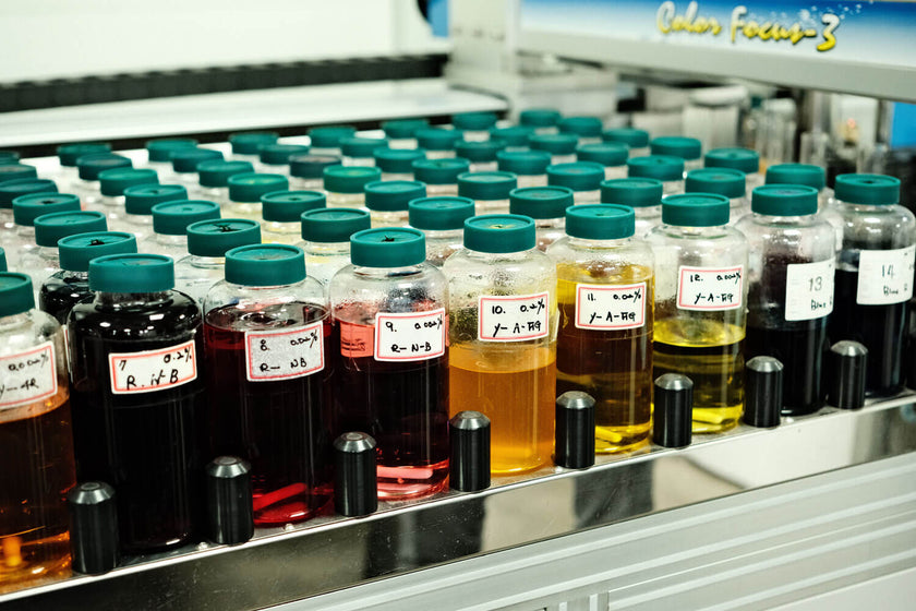 Row of labeled bottles with colored liquids in a laboratory testing machine.