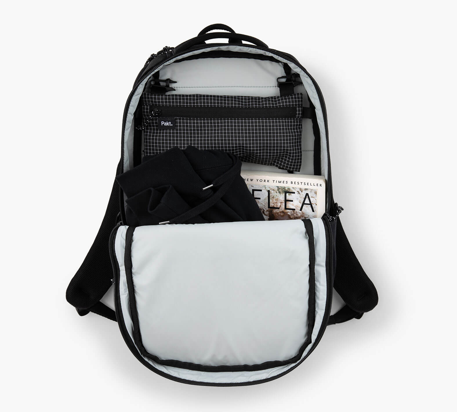 Open Everyday 22L backpack with front pocket holding black clothing and a folded newspaper reading "FLEA".