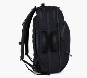Side view of a black Travel Backpack showing padded shoulder straps and multiple zippered compartments.