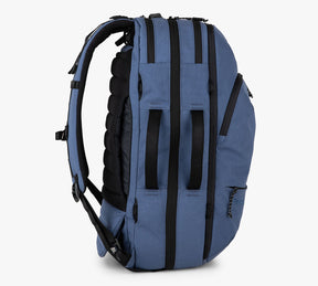 Blue travel backpack shown from the side with padded back and multiple straps