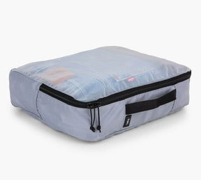 Light gray packing cube with zipper and side handle, clear top showing folded clothes