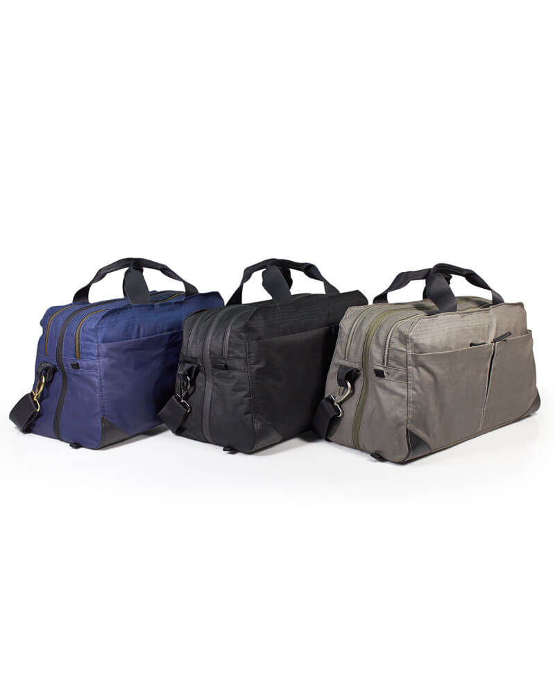 Three V1 Grandcart One Travel Duffels in blue, black, and gray colors with handles and shoulder straps, displayed on a white background.