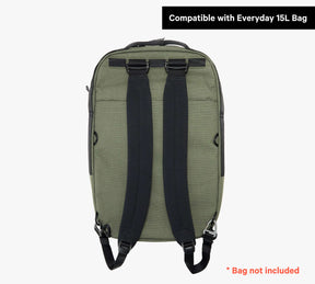 Back side of a green backpack with black straps, labeled 'Compatible with Everyday 15L Bag', note '* Bag not included'