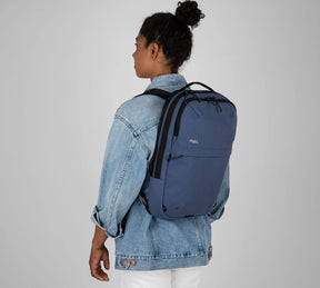 Person wearing a blue two-strap Everyday 15L Bag and a light denim jacket, shown from the back