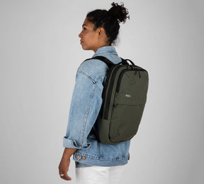 Profile of a woman wearing a green Everyday 15L Bag with black straps and a denim jacket, facing left