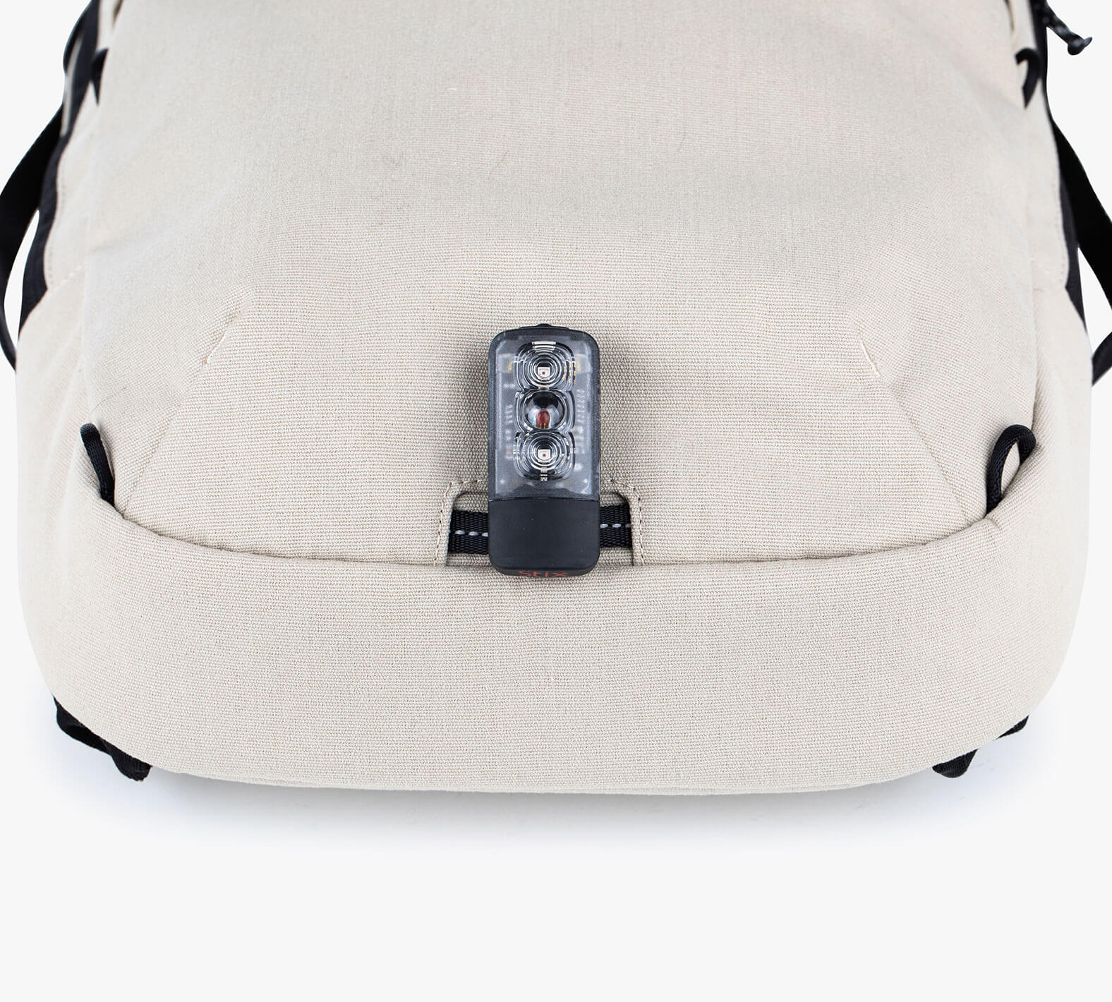 Close-up of the bottom of the Everyday 15L Bag with a small black bike light attached to the bag.