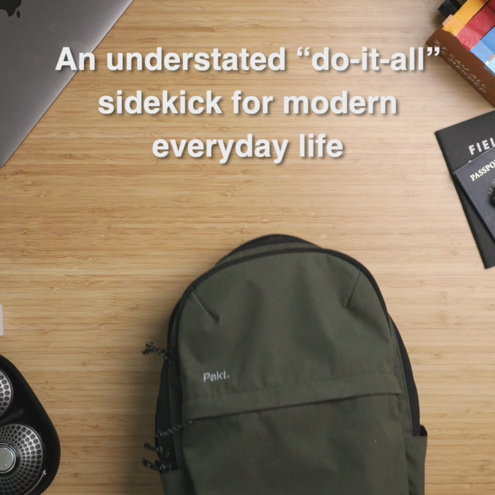 A Forest colored Everyday 22L Backpack with text 'An understated "do-it-all" sidekick for modern everyday life' on wooden surface