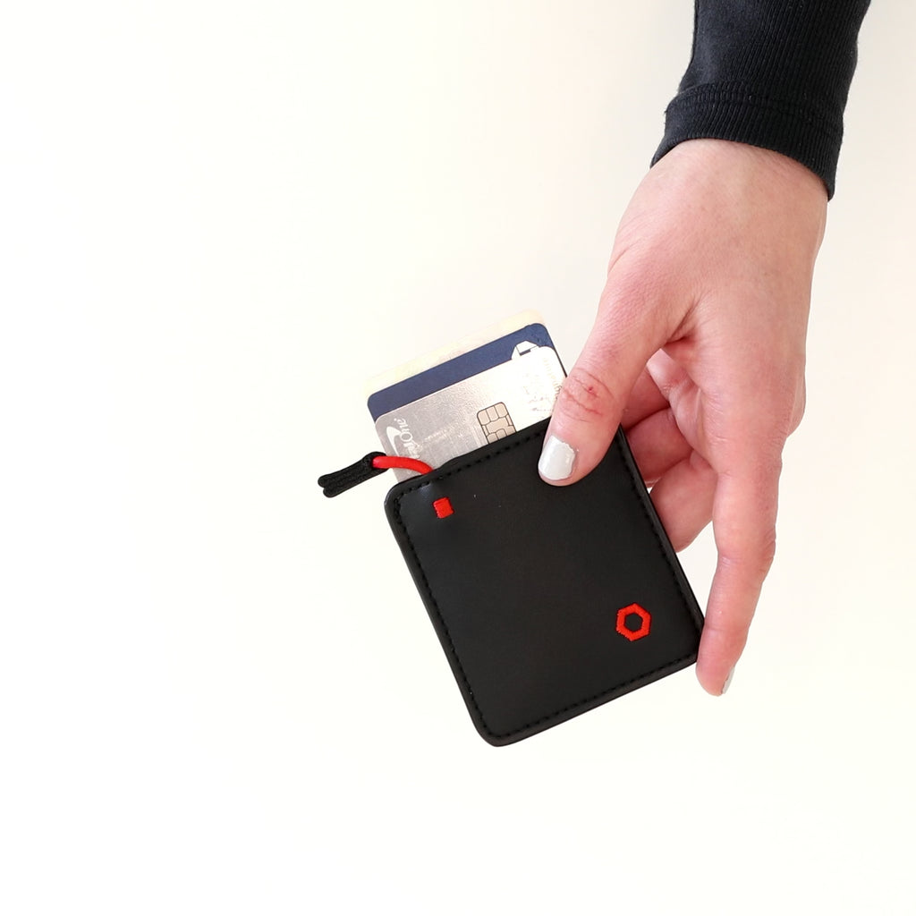 Hand holding a black Mojito Wallet with a card partially inserted