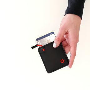 Hand holding a black Mojito Wallet with a card partially inserted