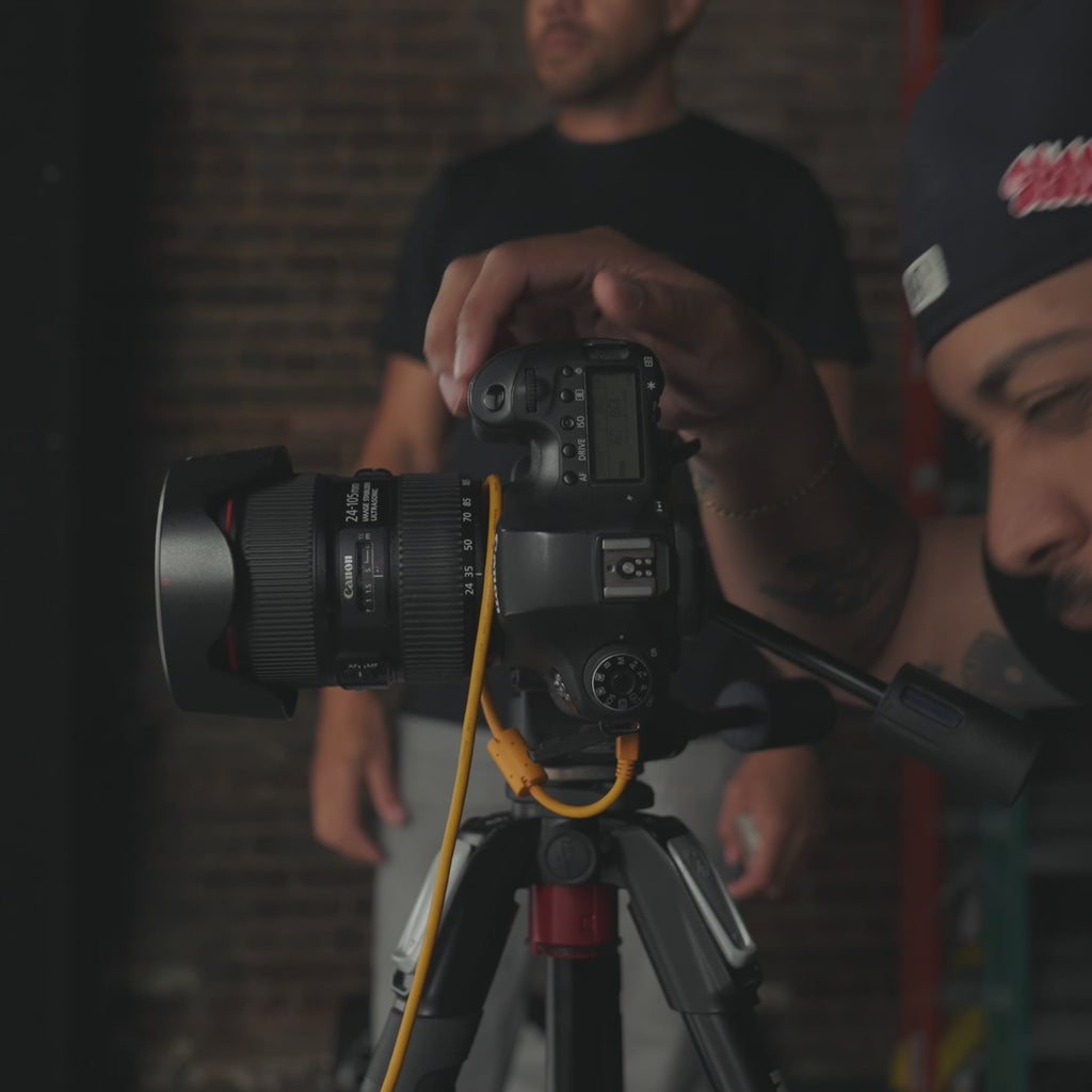 Person adjusting a camera mounted on a tripod indoors