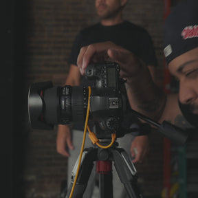 Person adjusting a camera mounted on a tripod indoors